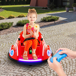 A young girl sits in a red remote-controlled bumper car toy on a paved outdoor driveway, holding toy ice cream cones. A pair of hands in the foreground holds a blue remote control.