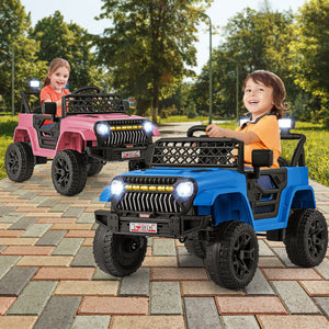 Two children playing with pink and blue toy jeeps on a paved area with trees in the background.