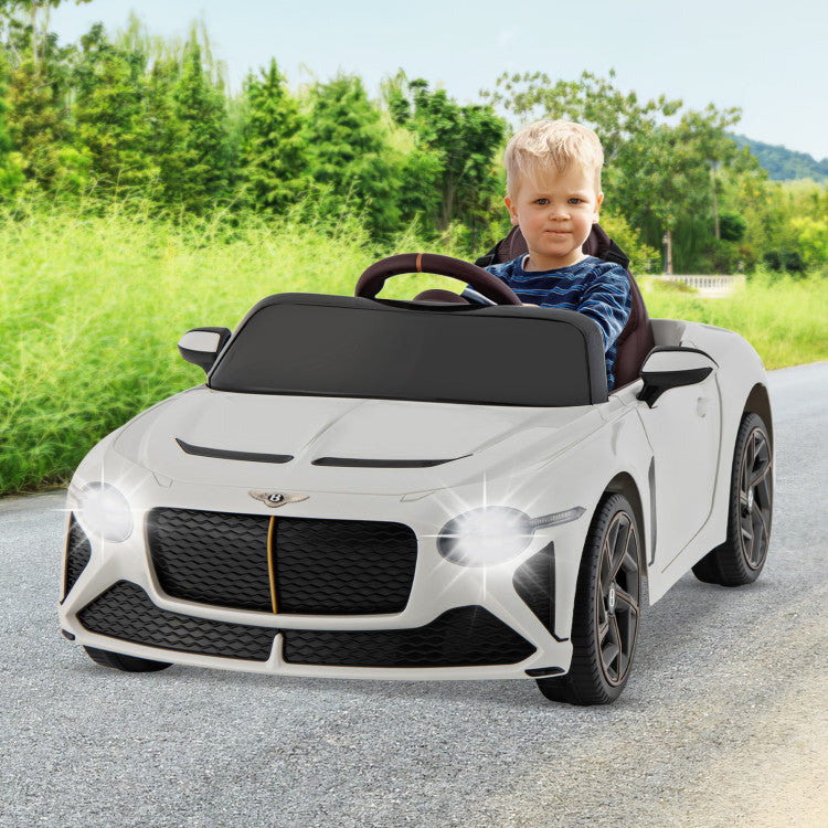 Child driving a toy Bentley car on a road with greenery in the background