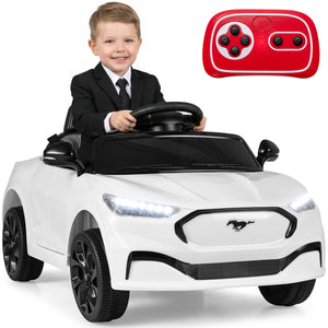 Child in a suit sitting in a white toy car with a remote control on a white background