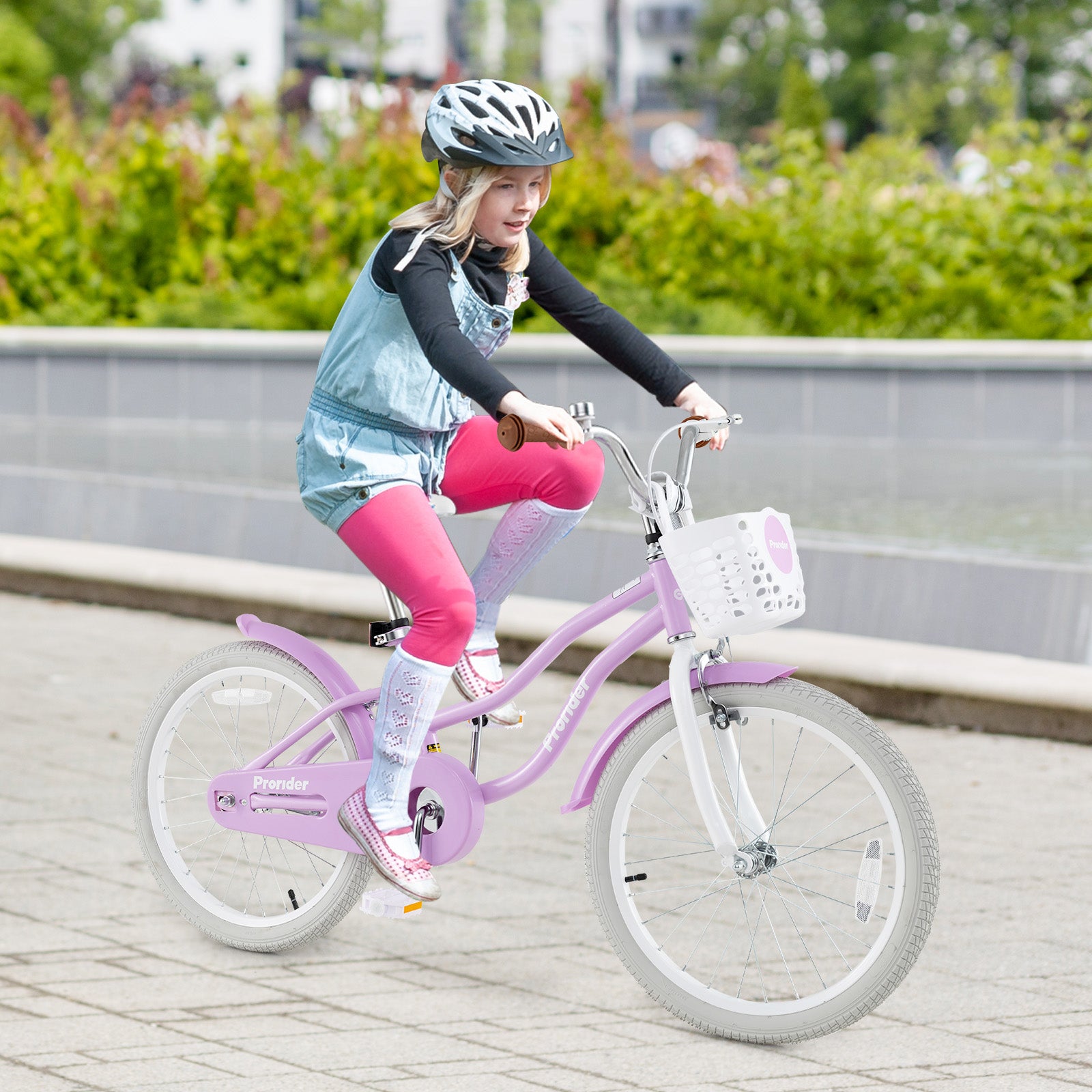 Child riding a pink bicycle with a helmet on a paved path.