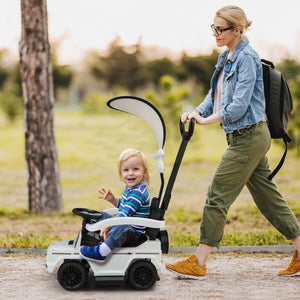 Woman pushing a child in a toy car through a park
