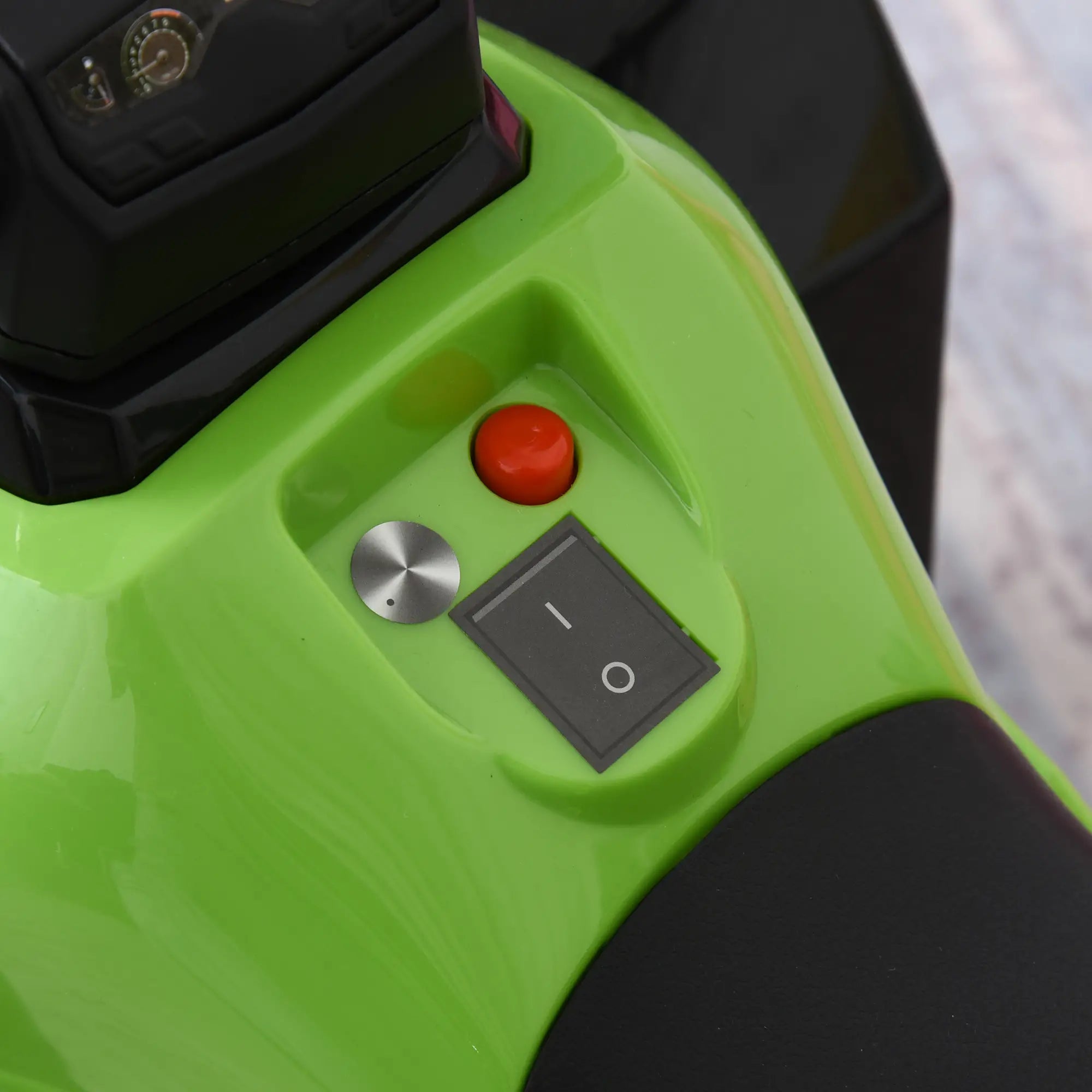 Close-up of a green device with control buttons including a red one and power switch.