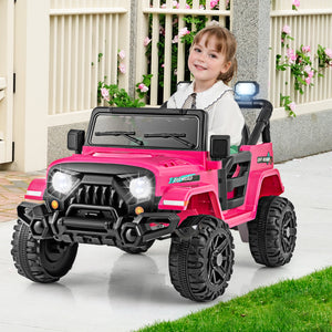 Child sitting in a pink toy jeep with a white fence and flowers in the background