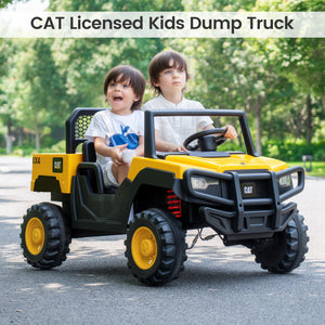 Two children playing in a CAT licensed kids dump truck on a road with trees in the background.