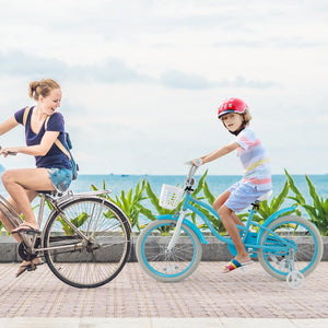 Woman and child riding bicycles by a coastal path with greenery and ocean view.