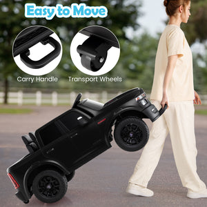 Black toy truck with carry handle and transport wheels, being pushed by a person outdoors.
