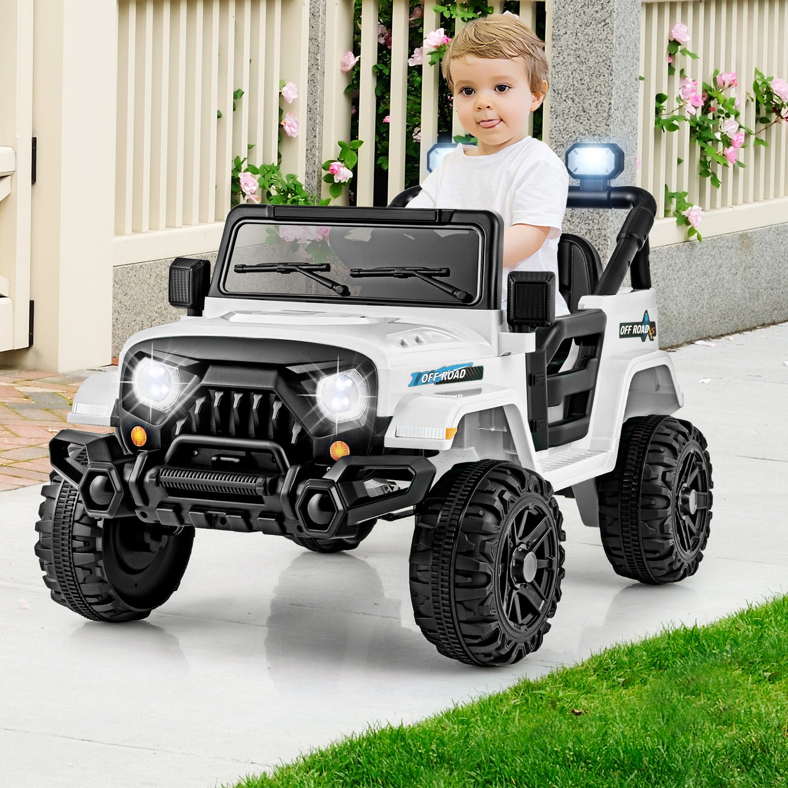 Child sitting in a toy jeep with lights on a patio