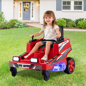 A young girl with blonde hair sitting in a red and black ride-on toy lawn mower with flashing blue lights, parked on a green grass lawn in front of a house.