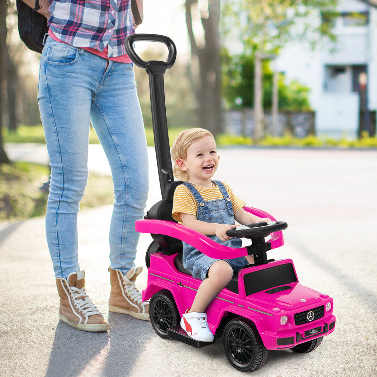 Child in a pink toy car with a person standing nearby on a road.