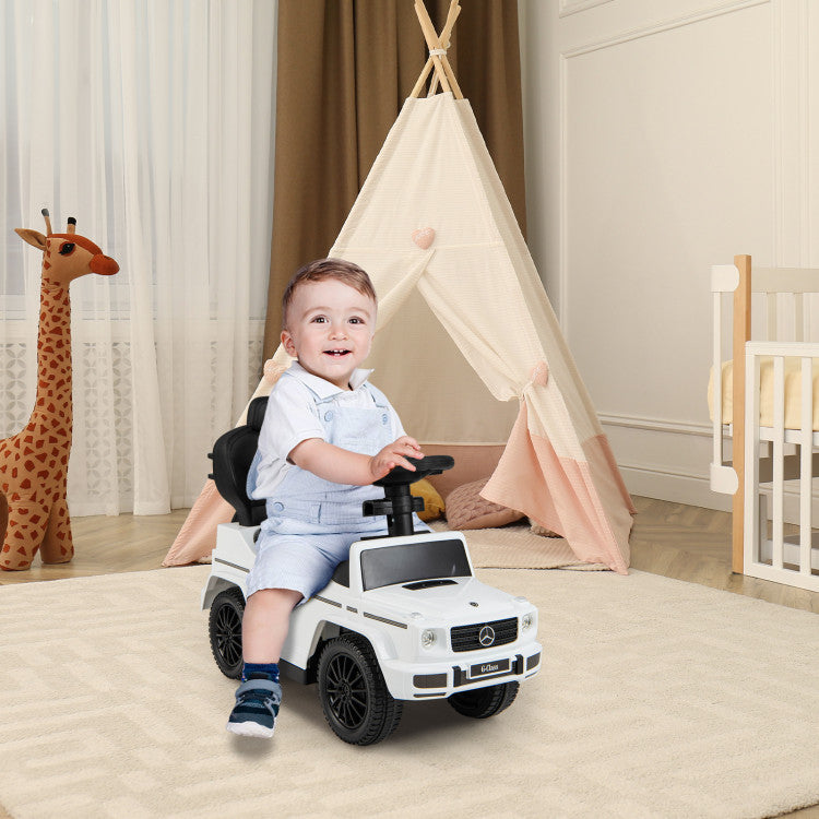 Child playing with a toy car in a room with a teepee and stuffed giraffe.