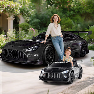 Woman and child with a black Mercedes-Benz car and a smaller model car in a garden setting