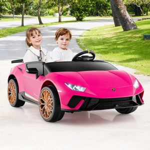 Two children in a pink toy car with a Lamborghini design on a road.
