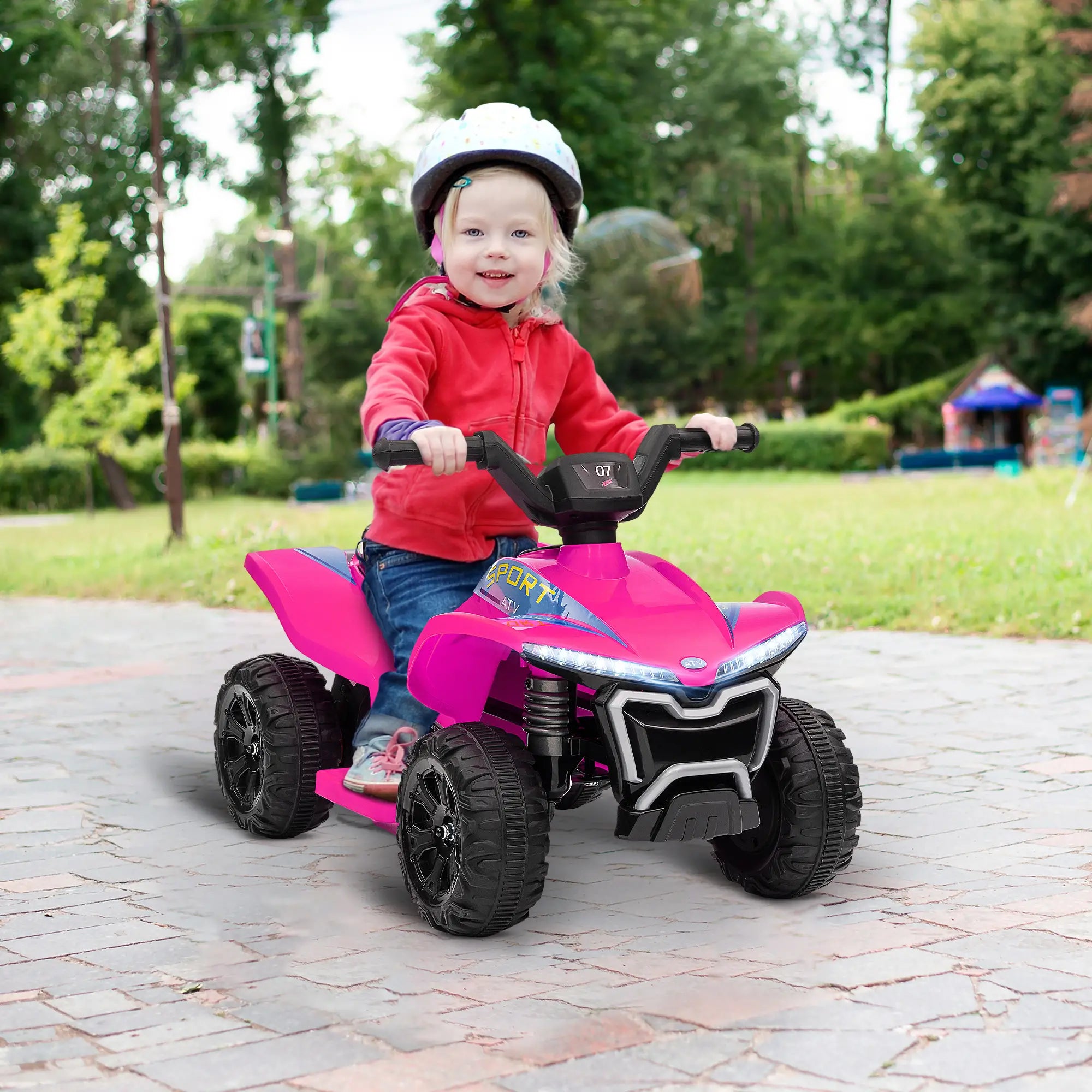 Child riding a pink toy ATV in an outdoor setting