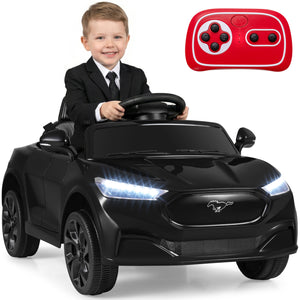 Child in a suit sitting in a toy car with a remote control on a white background