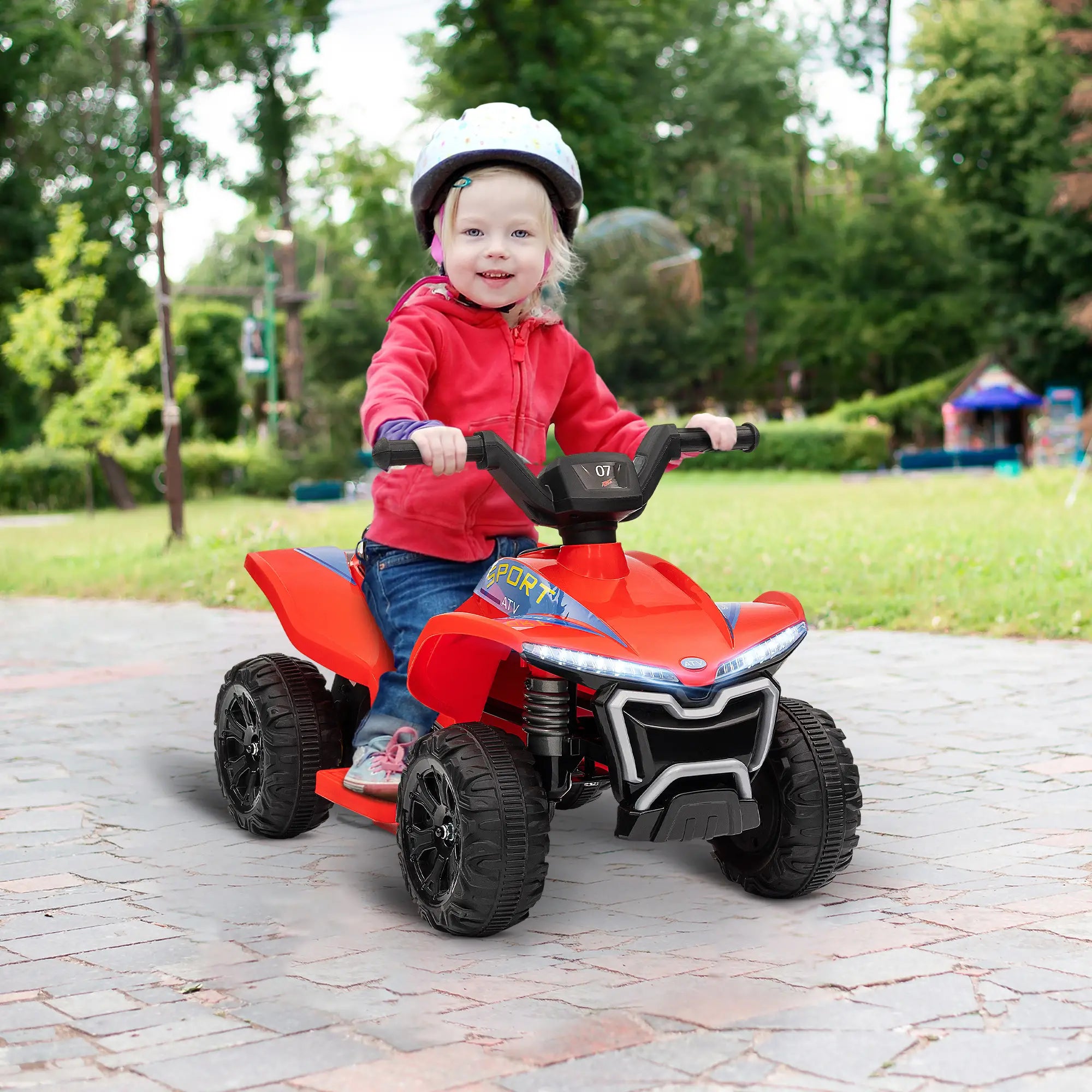 Child riding a red toy ATV in an outdoor setting