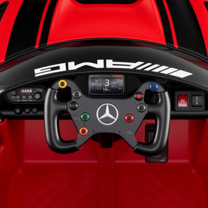 Close-up of a racing simulator steering wheel with AMG branding on a red background