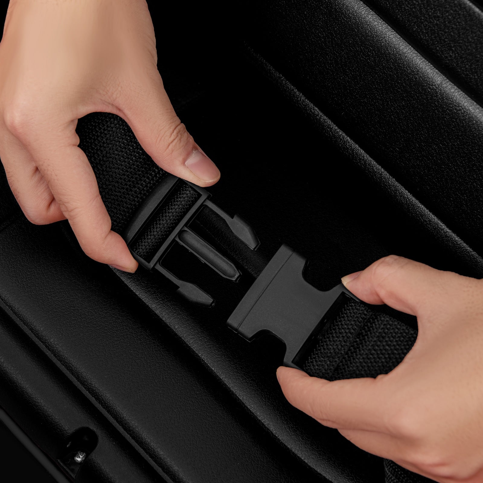 Close-up of hands securing a black suitcase handle.