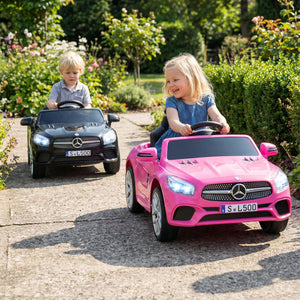 Two children playing with toy cars on a paved path in a garden.