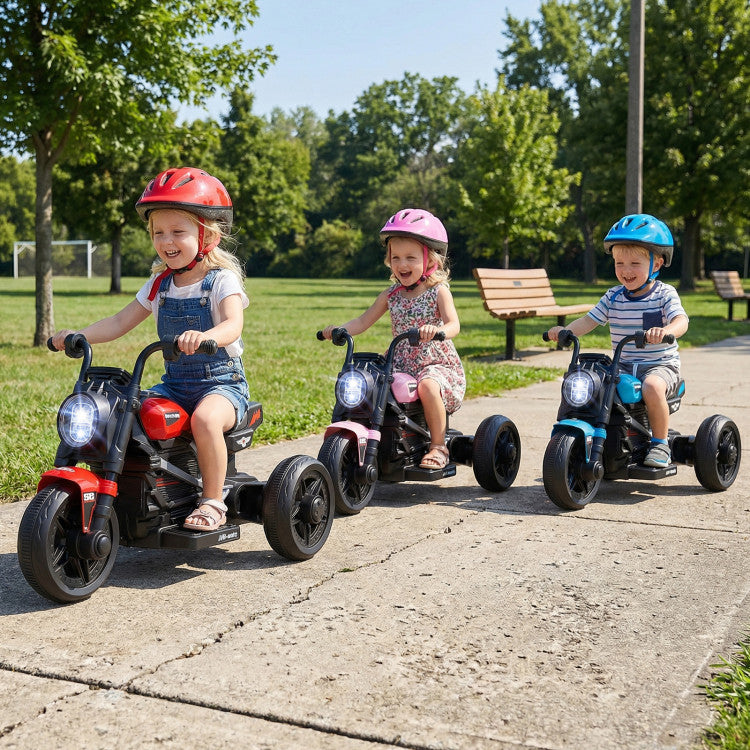 Three children riding toy motorcycles on a sidewalk with trees in the background