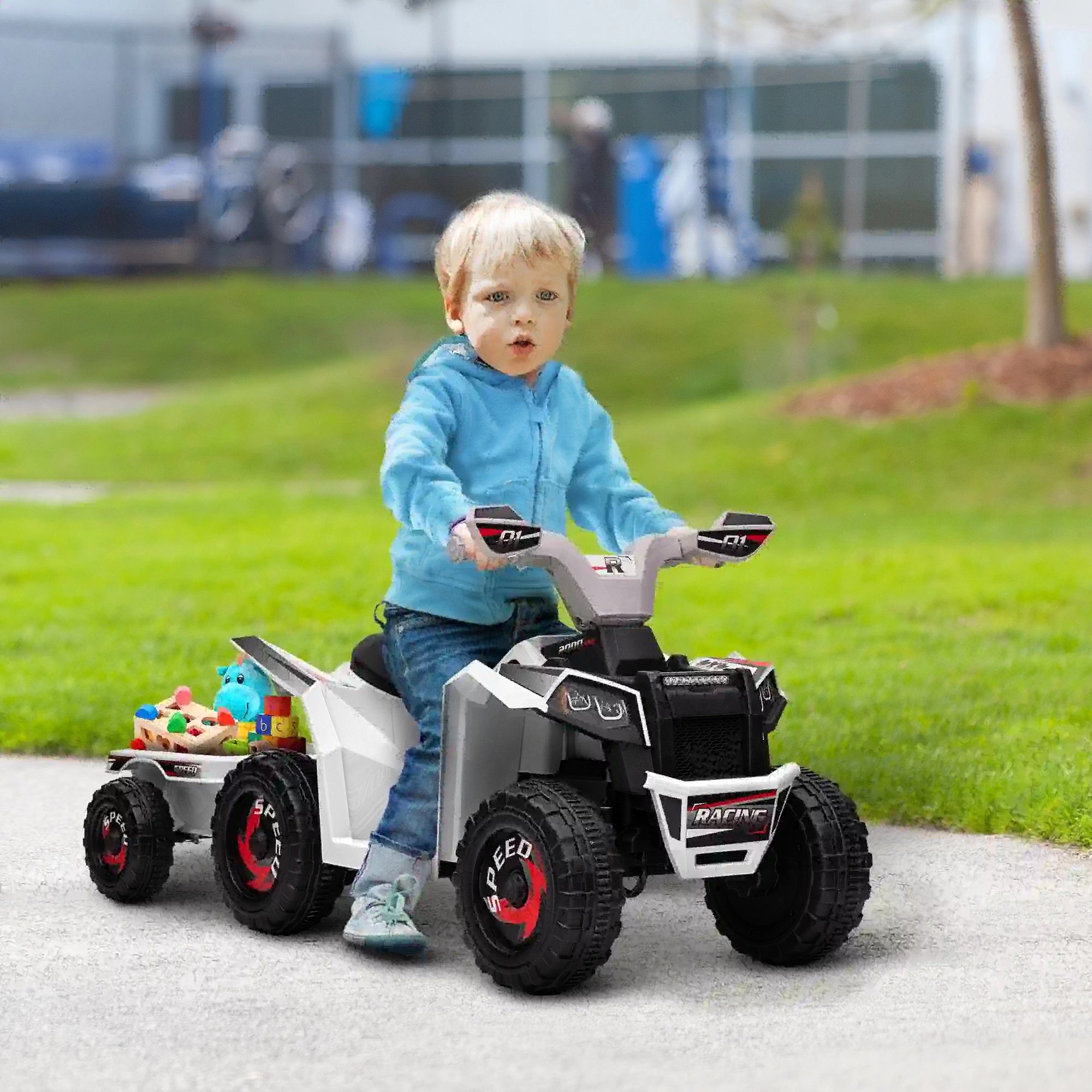 Child playing with a toy ATV outdoors on a paved area.