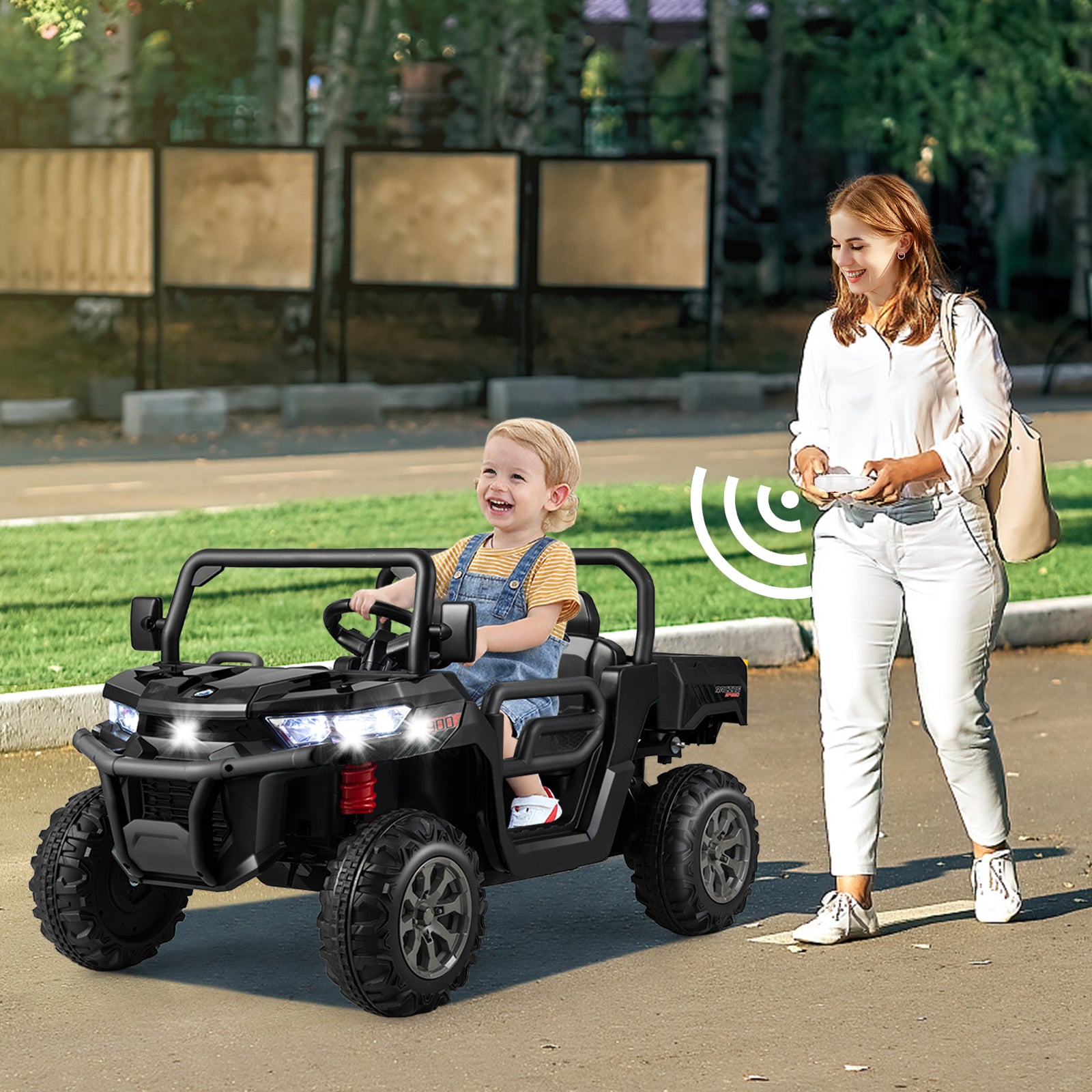Woman pushing a child in a toy car outdoors on a sunny day.