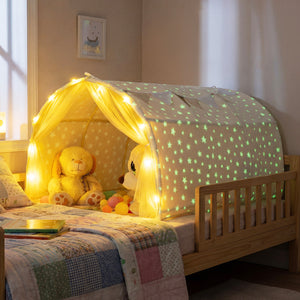 Children's bed with a star-patterned canopy and glowing lights, featuring toys and a teddy bear.
