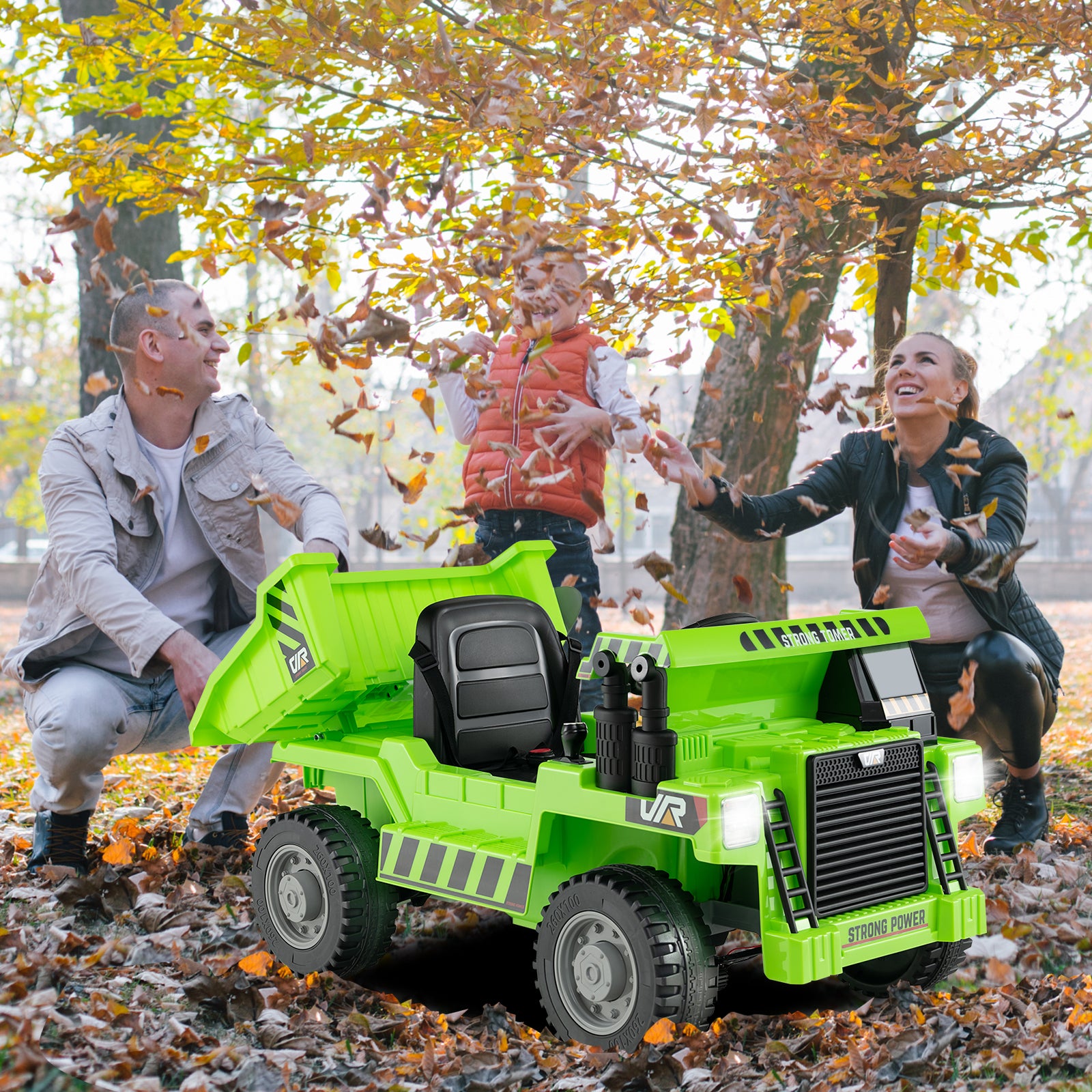 Green toy dump truck in a park with people playing in the background