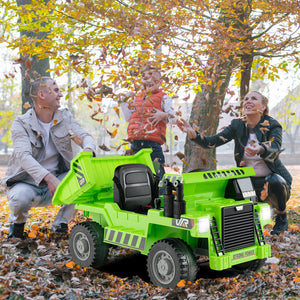 Green toy dump truck in a park with people playing in the background