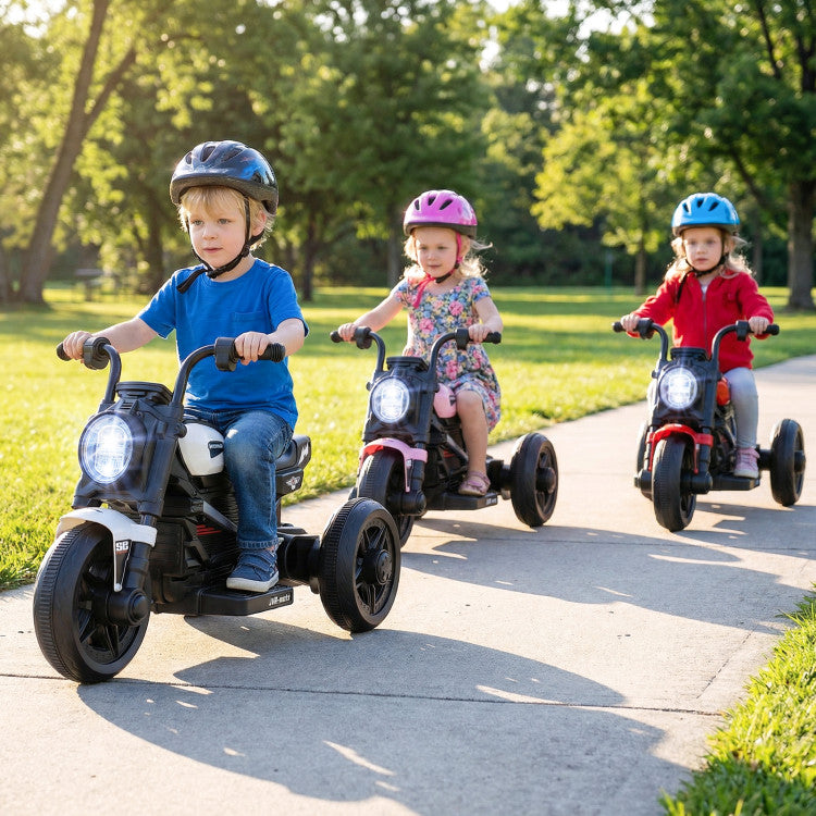 Three children riding tricycles on a paved path with trees in the background