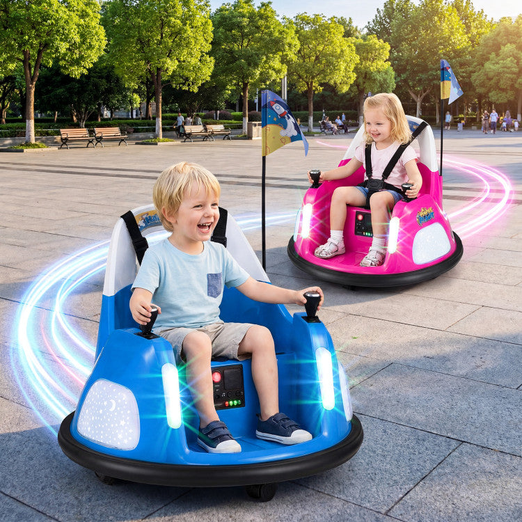 Two children playing in small electric bumper cars on a paved area with trees in the background.