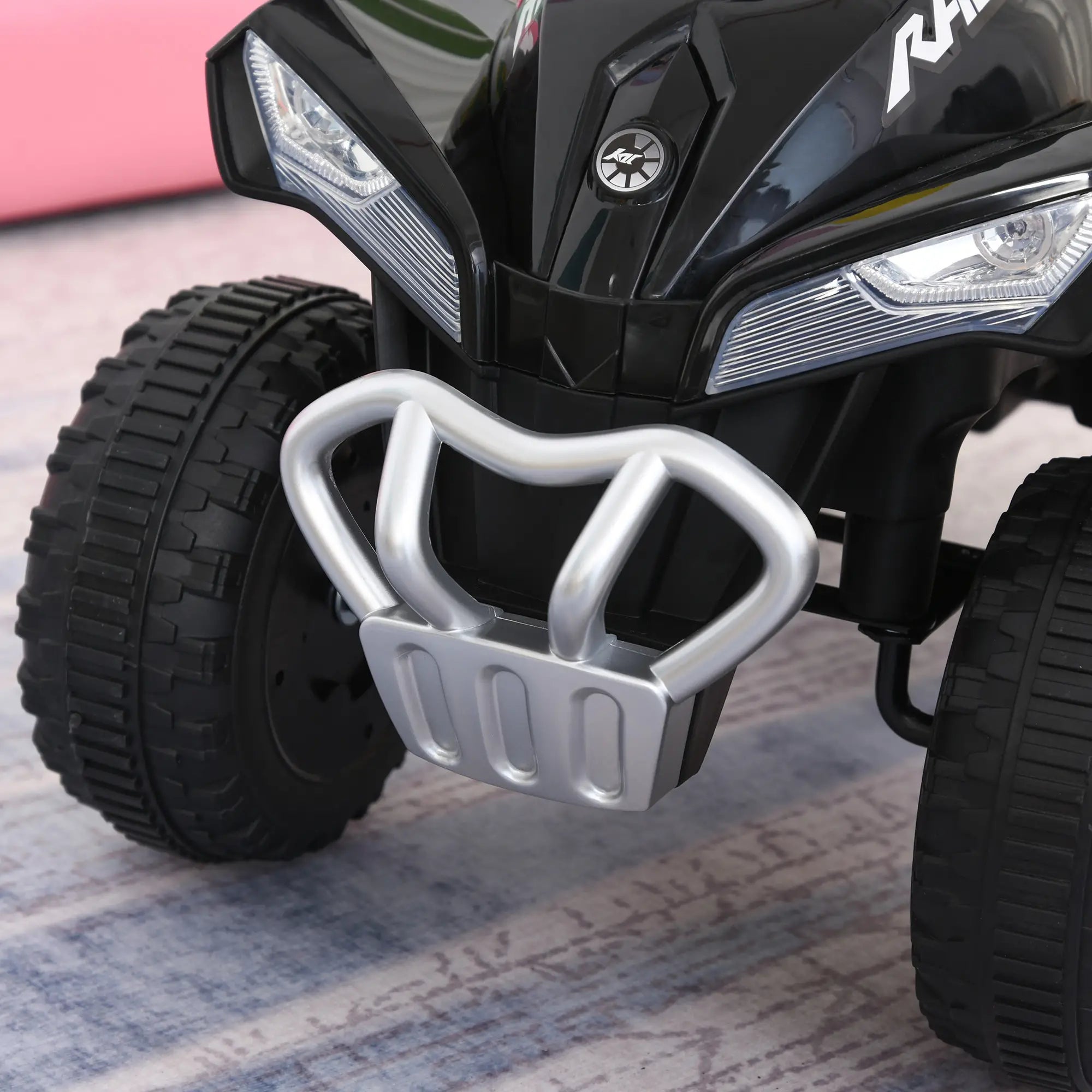 Close-up of a black ATV with a silver grille on a textured surface