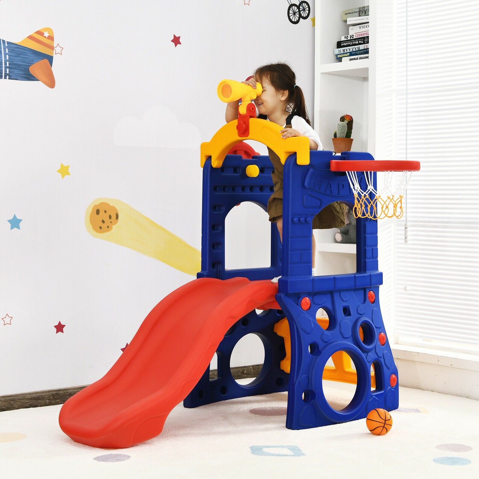 Children's playset with slides and basketball hoop in a room.