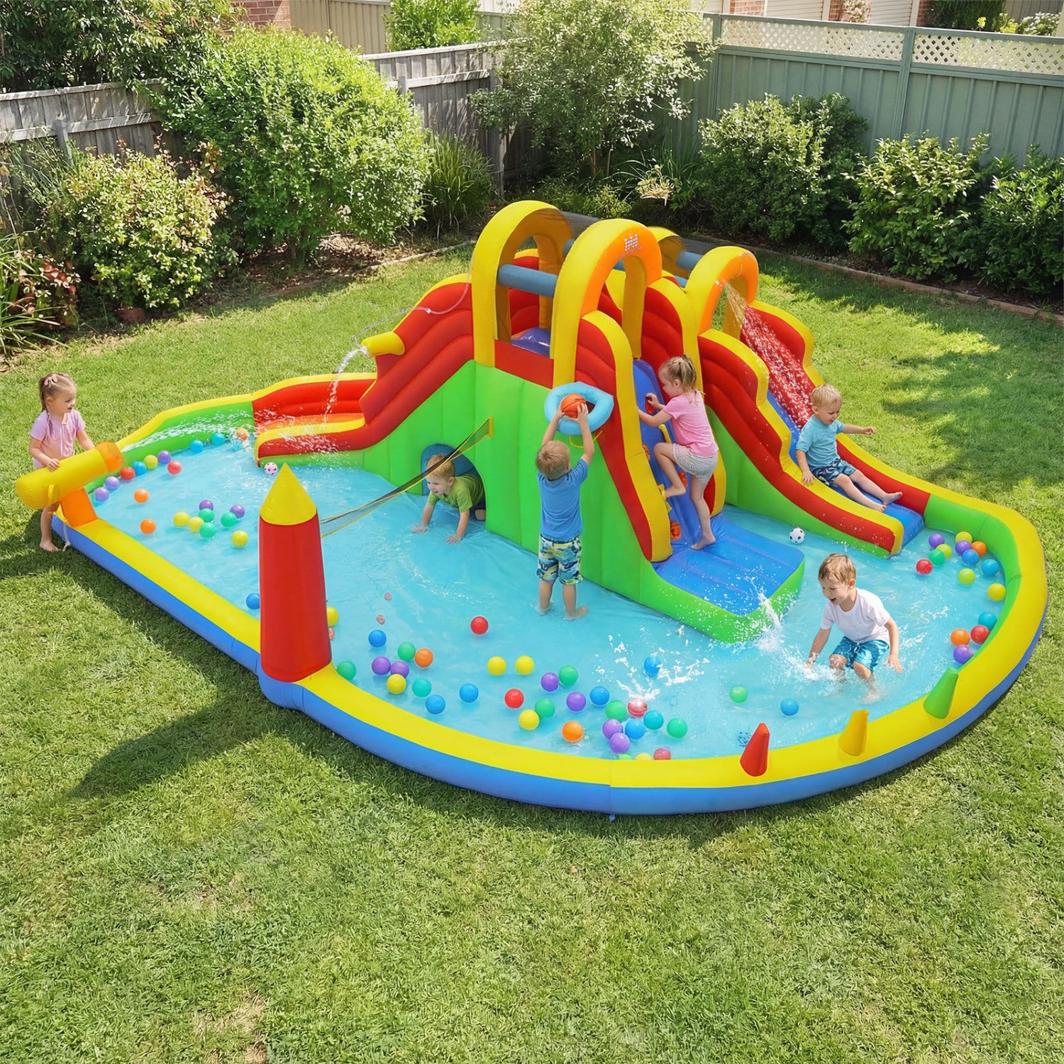 Children playing on a colorful inflatable water slide and pool in a backyard.
