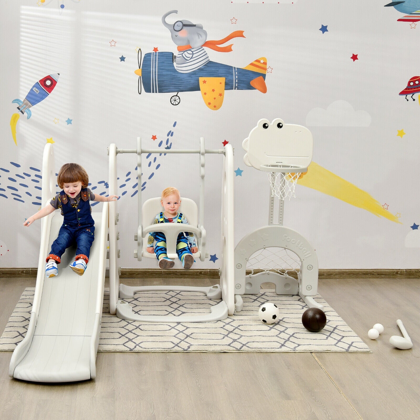 Children playing on a playground set with a colorful wall mural in the background.
