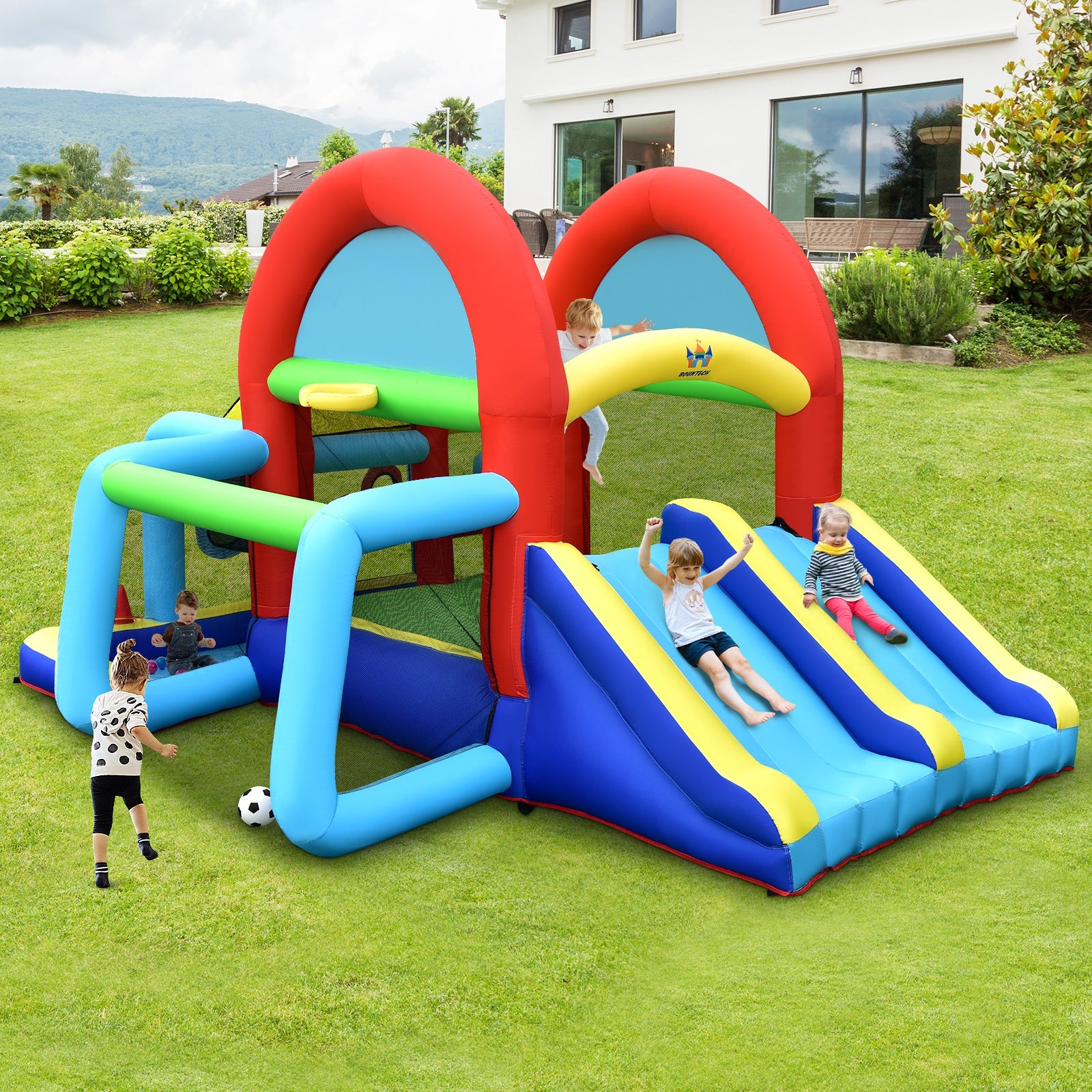 Children playing on a colorful inflatable playground structure in a backyard.