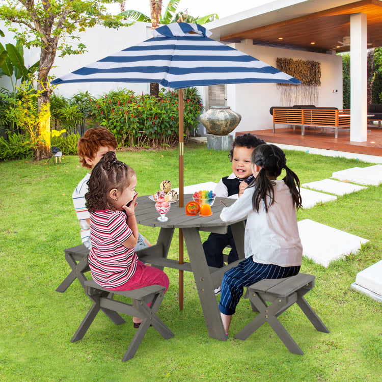 Children sitting at a picnic table with a striped umbrella in a garden setting