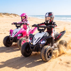 Two children riding ATVs on a sandy beach with ocean in the background