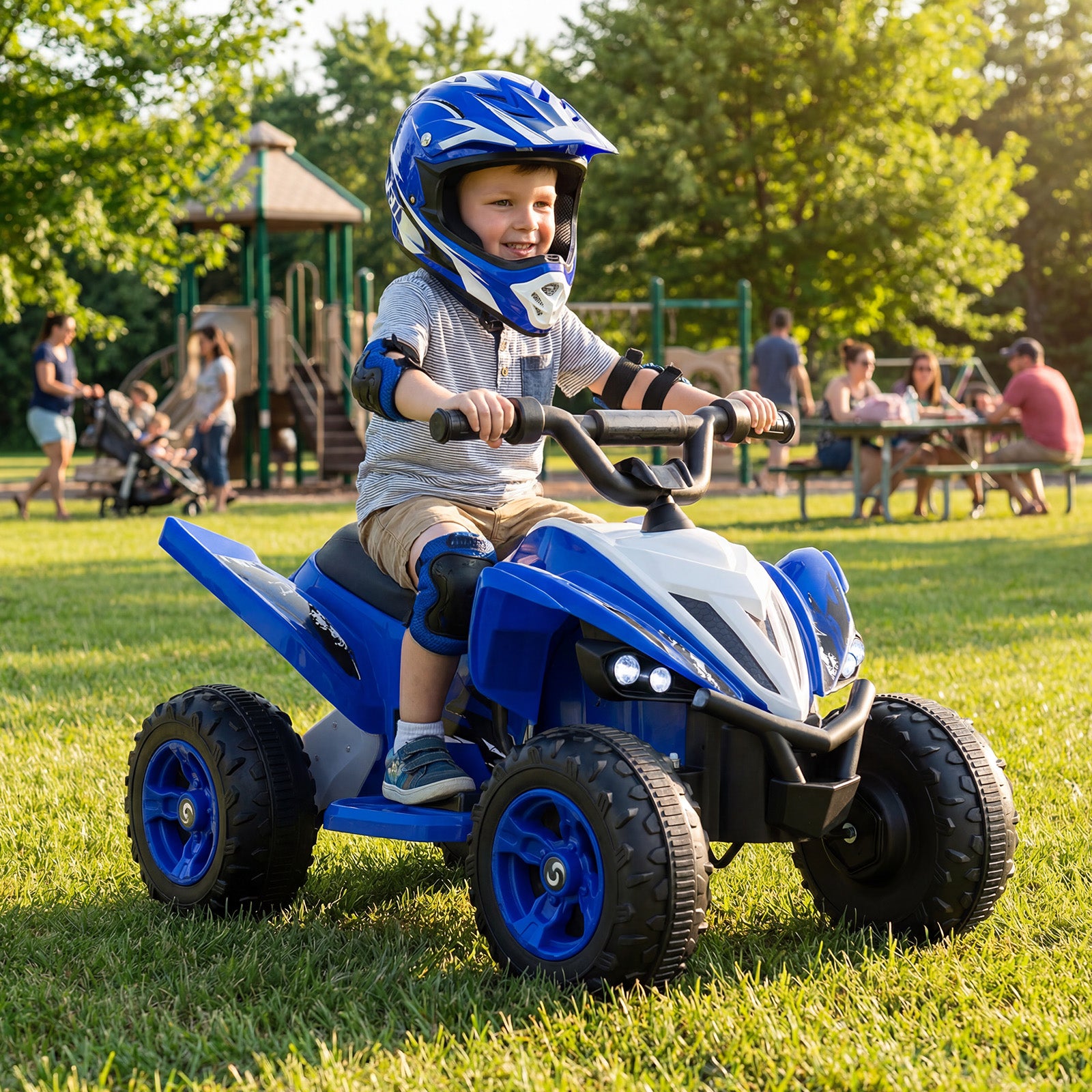 Child riding a blue toy ATV in a park with other people and playground equipment in the background.