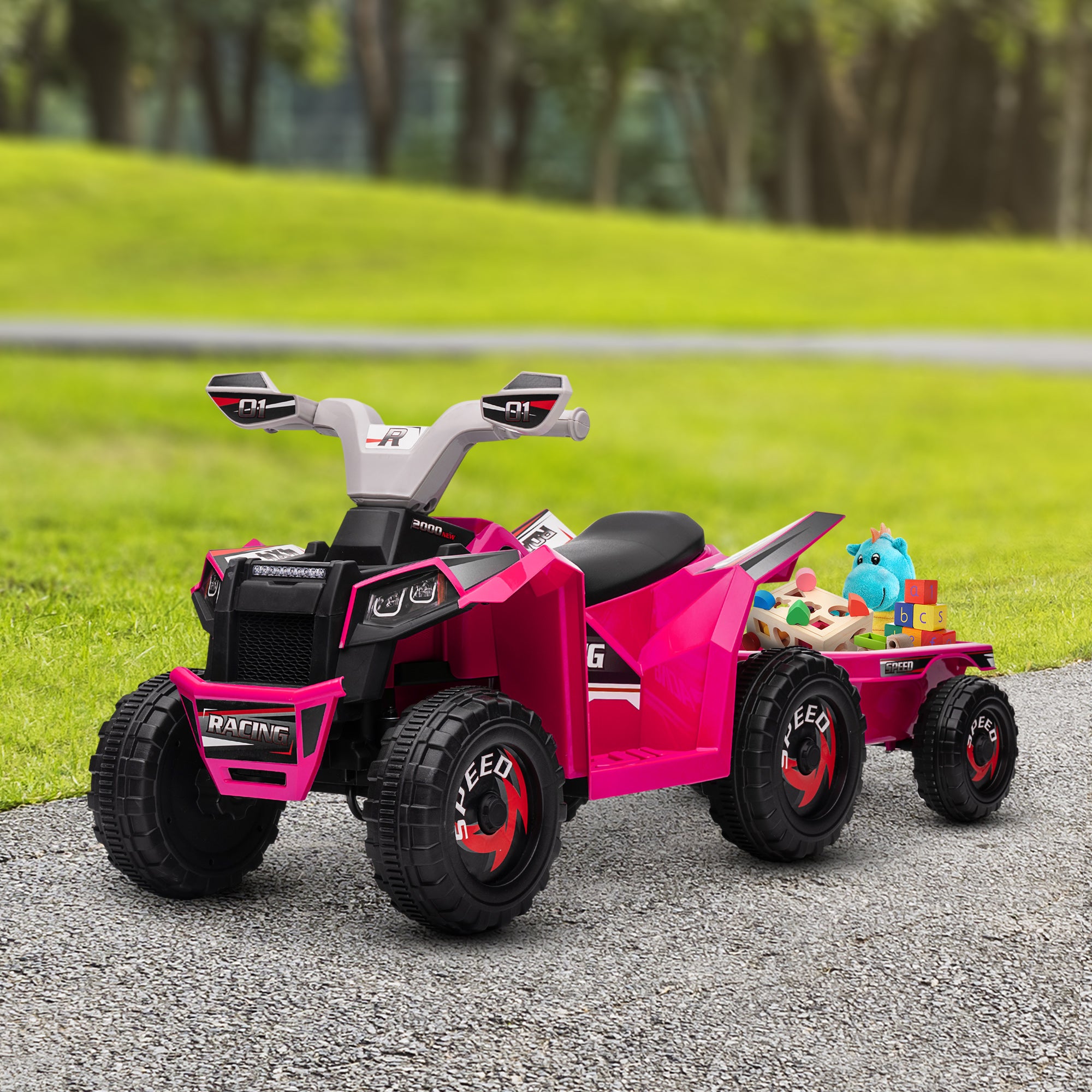 Pink toy ATV with a trailer on a gravel path in a park