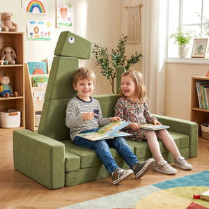 Two children sitting on a green dinosaur-shaped chair in a room with books and toys.