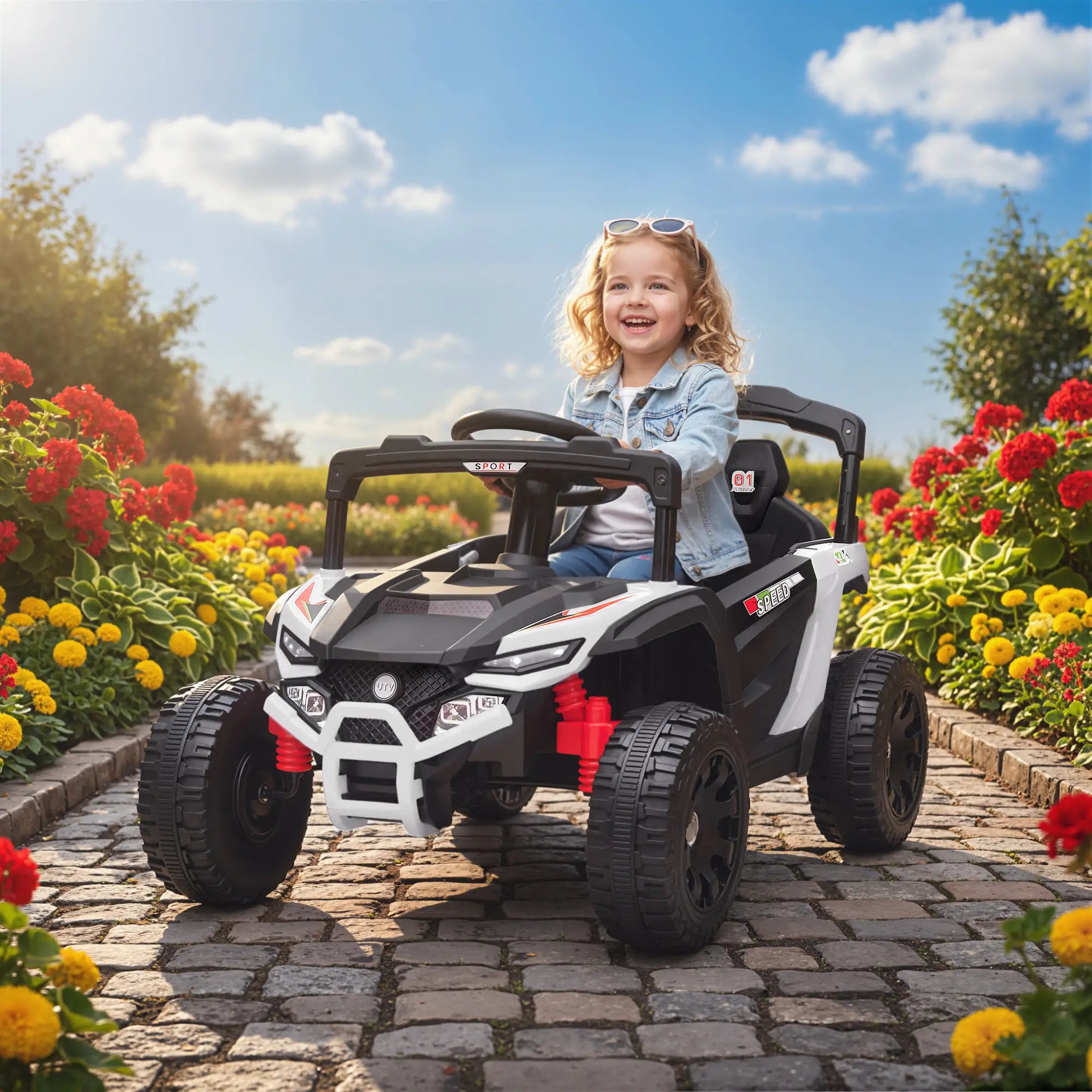 Child sitting in a toy car on a stone path with flowers and trees in the background