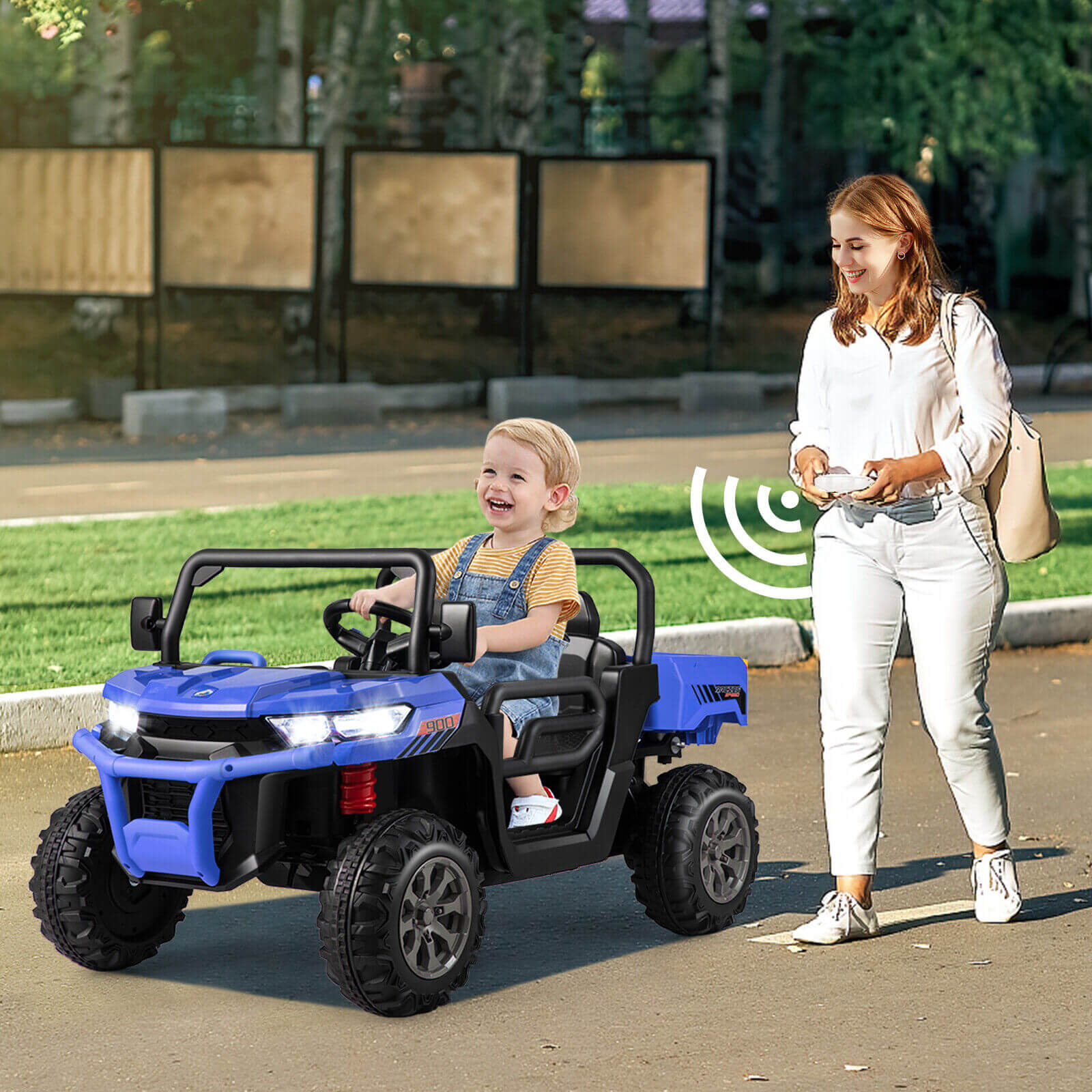 Child in a blue toy car being pushed by an adult on a sidewalk.