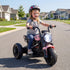 Child riding a pink toy motorcycle on a suburban street