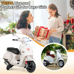 Child receiving a Vespa toy scooter as a gift from a woman, with festive decorations in the background.