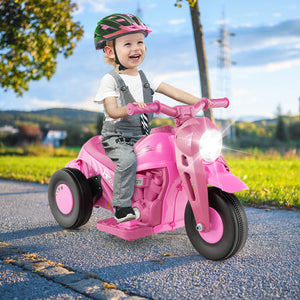 Child riding a pink toy motorcycle outdoors on a sunny day