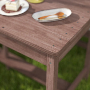 Wooden table with plates of food on a grassy background