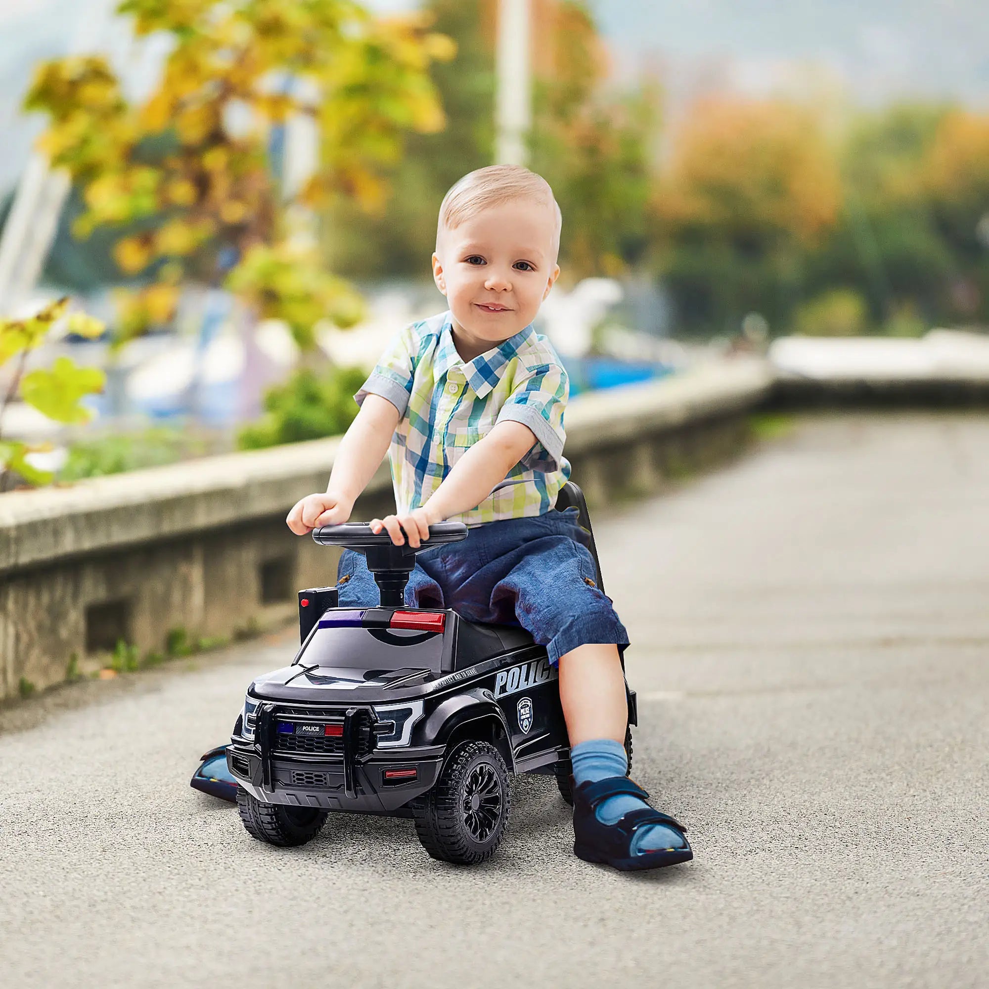 Child riding a toy police car outdoors on a sunny day