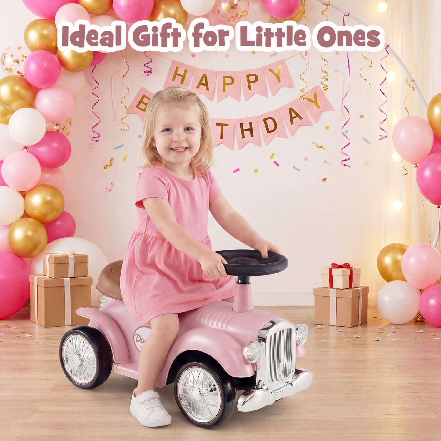 Child in a pink dress riding a toy car with balloons and birthday decorations in the background