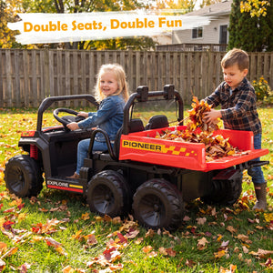 Two children playing with a red toy truck in a backyard during autumn.
